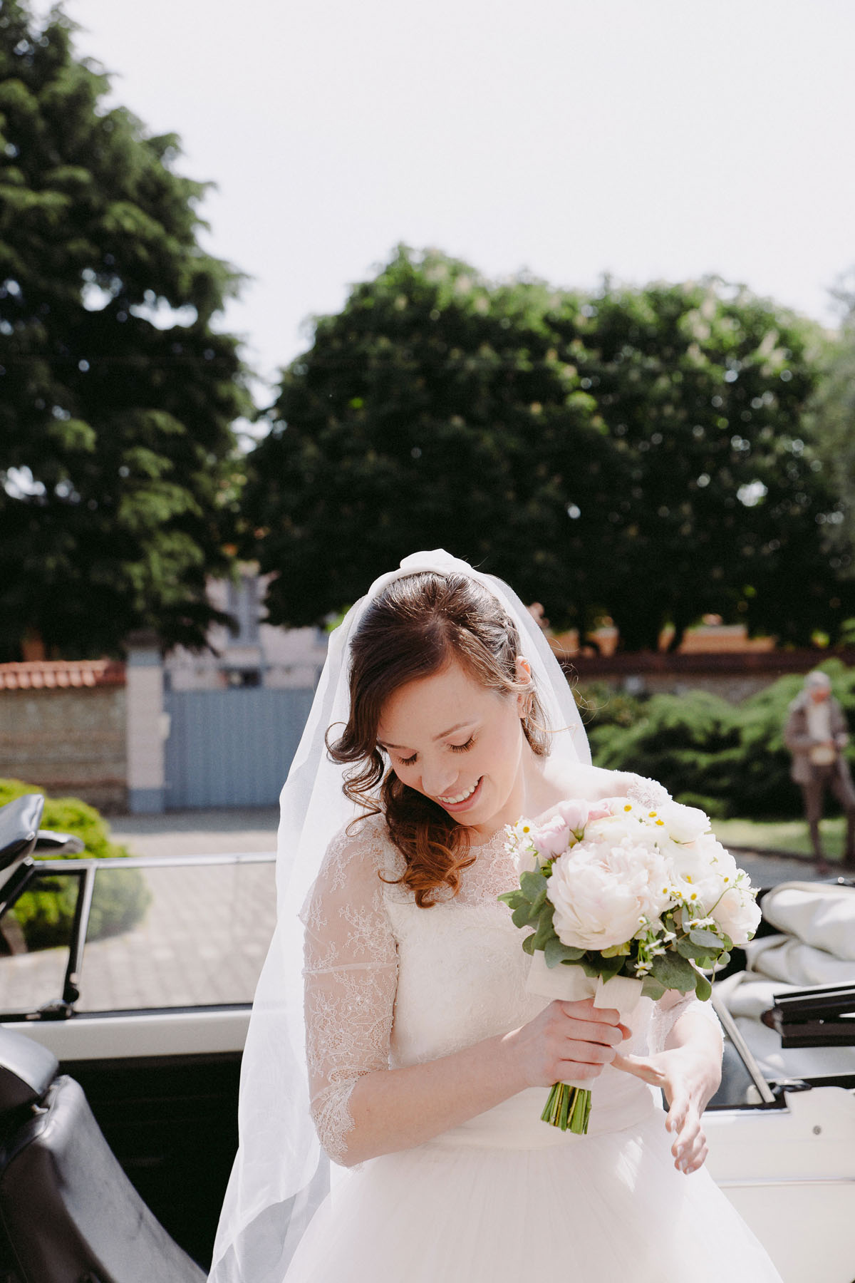 abito da sposa con maniche in pizzo e bouquet dai colori pastello